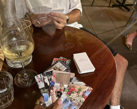 Friends playing cards from a Mimies photo deck over drinks
