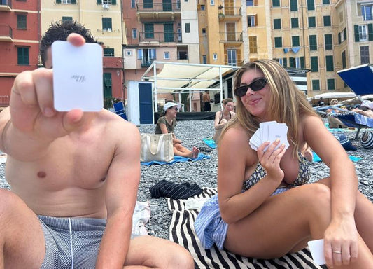 Couple on the beach holding up their personalised photo playing cards
