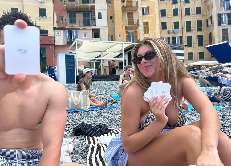 Group of friends on the beach holding up a photo playing card deck