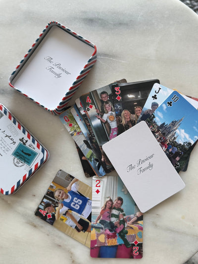 Custom family photo playing cards spread around their airmail-style tin