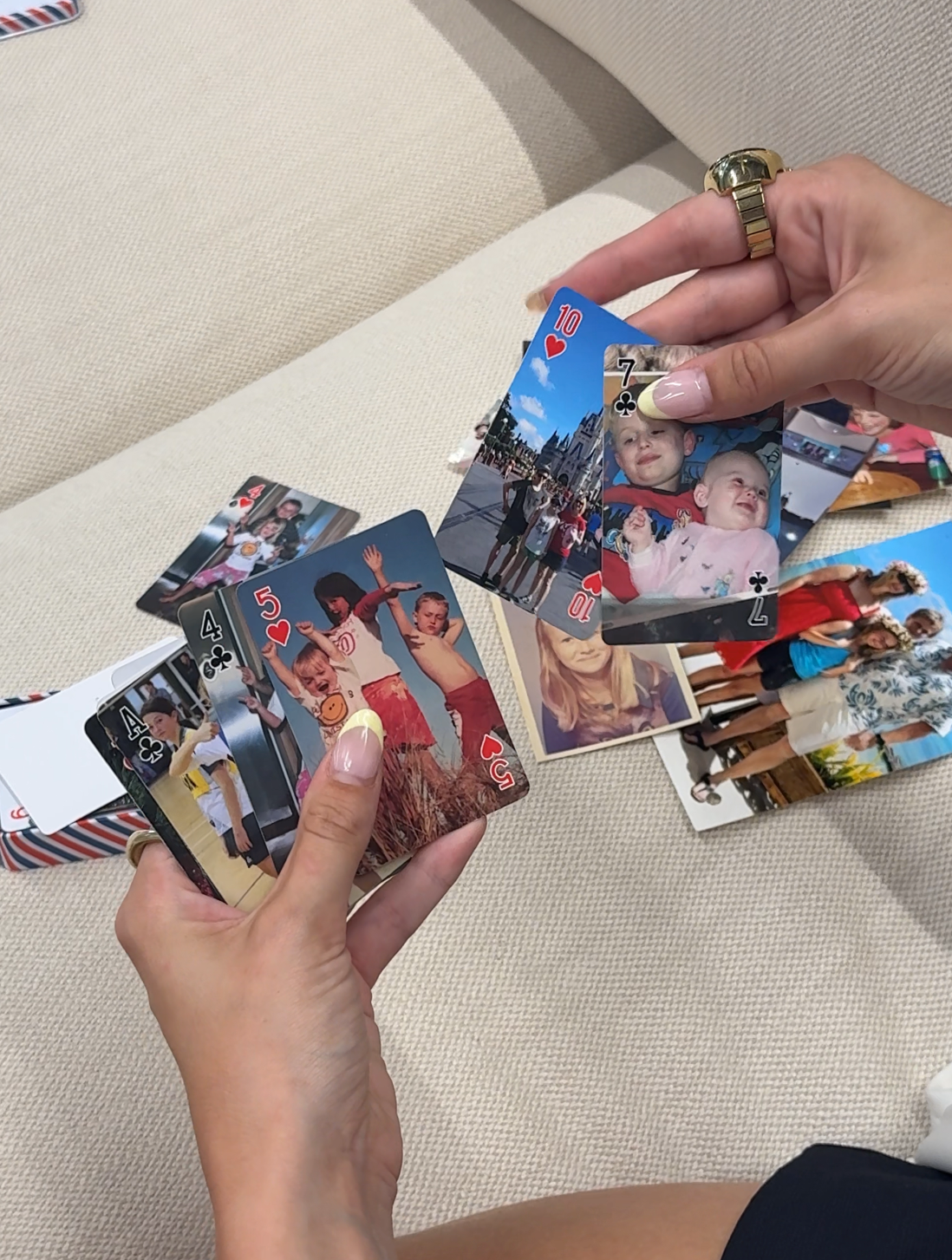 Two hands fanning a deck of playing cards printed with family photos